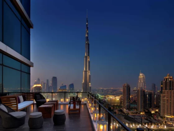 Rooftop terrace with seating and glowing lanterns overlooking Dubai skyline and the Burj Khalifa at dusk.