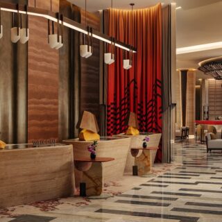 Hotel reception area with curved stone desk, warm pendant lights, and red drapes in a stylish lobby.
