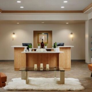 Spa reception area with a wooden front desk, beige walls, and orange lounge chairs.