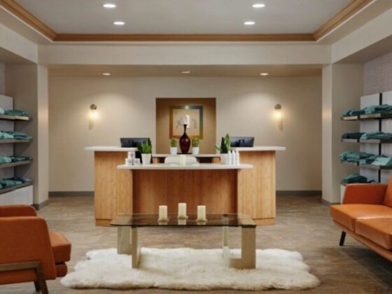Spa reception area with a wooden front desk, beige walls, and orange lounge chairs.