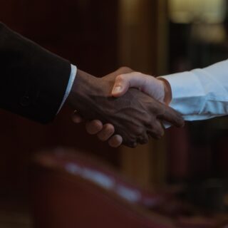 Two people shake hands in a close-up, symbolizing a business agreement or partnership.