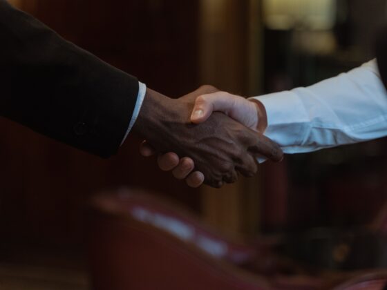 Two people shake hands in a close-up, symbolizing a business agreement or partnership.