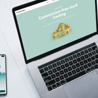 Laptop screen shows Wealthsimple Trade promo for commission-free stock trading on a mint background, with a gold bridge model.