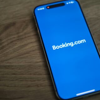 Close-up of a smartphone screen showing the Booking.com app on a bright blue background.