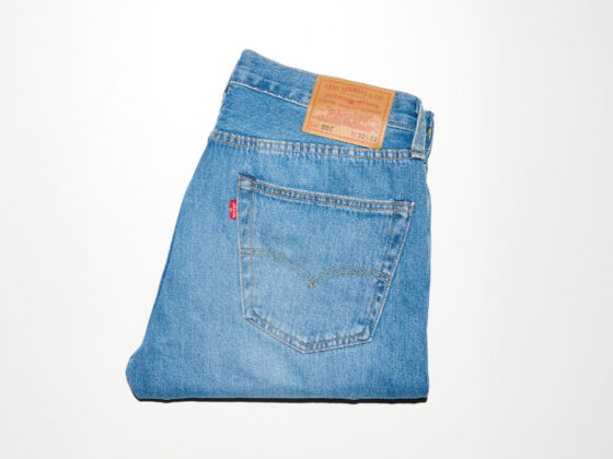 Back pocket of blue denim jeans with a red Levi's tag and tan leather patch near the waistband area.