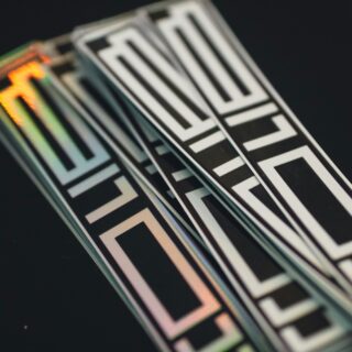Close-up of iridescent, geometric black-and-white patterned ribbons against a dark background with reflective edges.