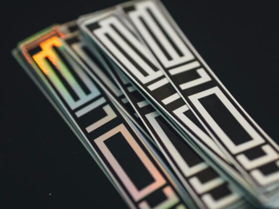 Close-up of iridescent, geometric black-and-white patterned ribbons against a dark background with reflective edges.