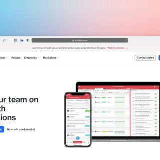 Airtable homepage hero with a laptop and phone showing automations workflow on a white page against a gradient backdrop.