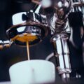 Close-up of chrome motorcycle handlebars with a stream of coffee pouring into a white mug beneath.