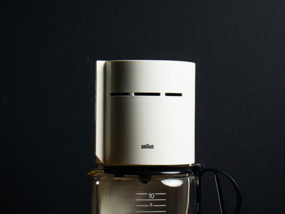 White Braun drip coffee maker with a glass carafe on a wooden table against a dark background, logo visible on the machine.
