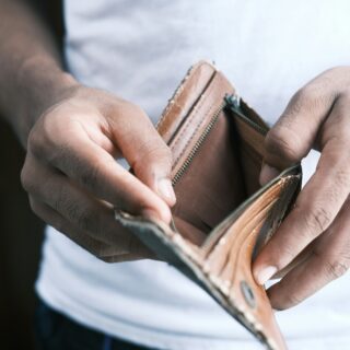 Close-up of hands opening a brown leather wallet with a zipper, revealing empty slots.