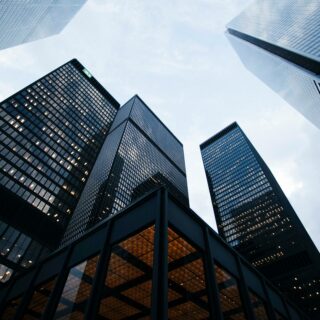 Low-angle view of tall glass skyscrapers converging toward the sky.
