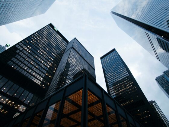 Low-angle view of tall glass skyscrapers converging toward the sky.