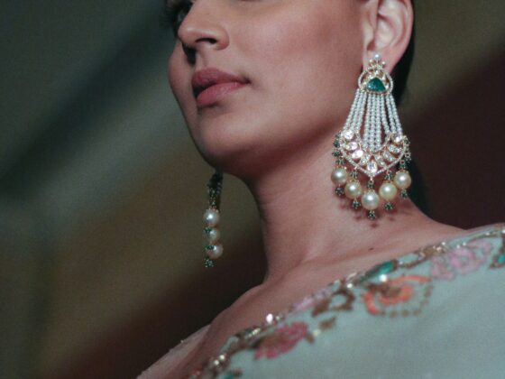 Close-up portrait of a woman wearing elaborate pearl chandelier earrings and makeup.