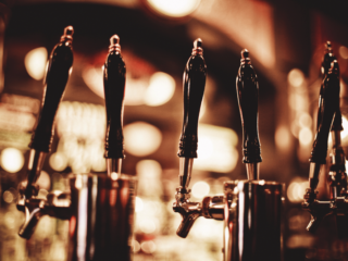 Row of beer taps with dark handles in a warmly lit bar.