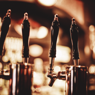 Row of beer taps with dark handles in a warmly lit bar.