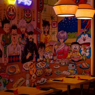 Colorful anime-style mural inside a ramen shop, showing customers eating, neon RAMEN sign, and hanging lamps.