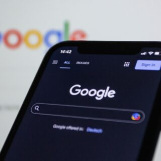 Close-up of a smartphone showing the Google search app, with the Google logo blurred in the background.