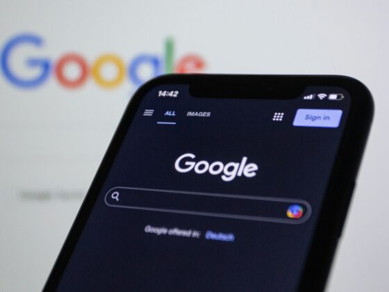 Close-up of a smartphone showing the Google search app, with the Google logo blurred in the background.