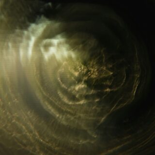 Abstract close-up of a gold-toned circular swirl with dark edges and soft light reflections.