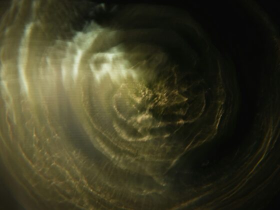 Abstract close-up of a gold-toned circular swirl with dark edges and soft light reflections.