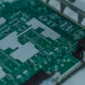 Close-up of a green printed circuit board with solder pads, traces, and connectors.