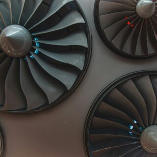 Close-up of large airplane turbine blades inside a jet engine, metallic grey with blue reflections.