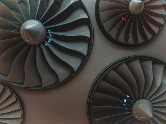Close-up of large airplane turbine blades inside a jet engine, metallic grey with blue reflections.