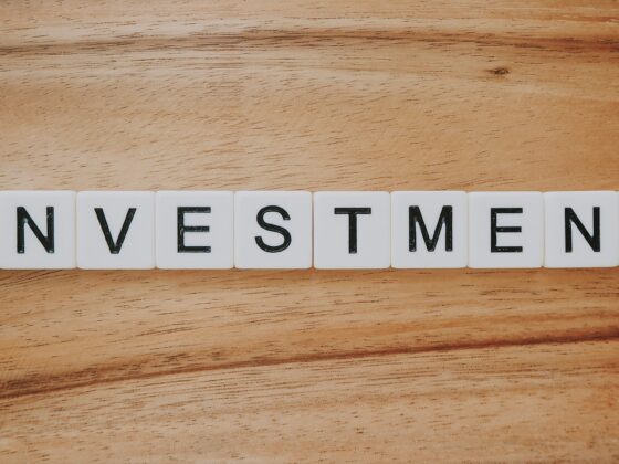 Tiles spell out the word INVESTMENT on a wooden surface