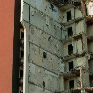 Partial demolition of a multi-story building with peeling plaster, exposed concrete, and graffiti on the upper walls.