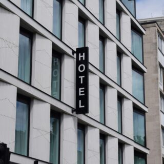 Modern hotel facade with vertical black sign reading 'HOTEL' on a white paneled building facade