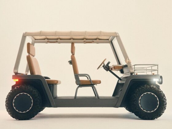 Side profile of a beige four-seat golf cart with tan upholstery, a beige canopy, and large rugged tires.