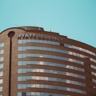 Curved brick Hyatt Regency hotel facade with many horizontal windows against a clear blue sky.