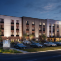 Exterior view of Hyatt Studios hotel at dusk with an illuminated entrance and parked cars in front.