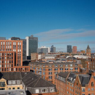 City skyline with brick and glass buildings under a clear blue sky; low-angle view of rooftops and high-rises along the horizon