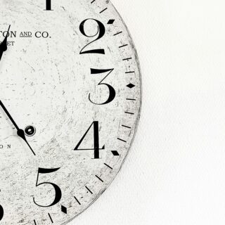 Close-up of a weathered clock face with bold black numerals and hands, and 'London 1894' text visible on the left.
