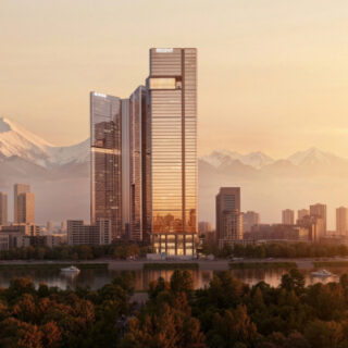 Golden sunset over a modern city skyline with tall glass towers by a river; distant mountains and a pagoda on the right.