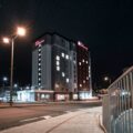 Nighttime exterior of a Hilton Garden Inn with lit windows, streetlights, and a star-filled sky.