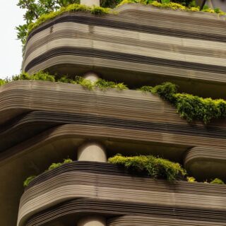 Curved, layered concrete building with green plants on each terrace.