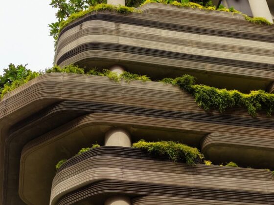 Curved, layered concrete building with green plants on each terrace.