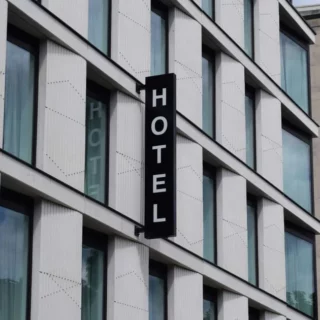 Vertical black hotel sign reading 'HOTEL' on a modern white building facade.