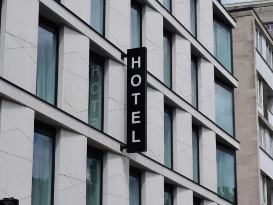 Vertical black hotel sign reading 'HOTEL' on a modern white building facade.