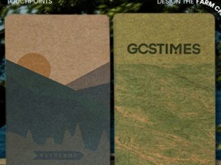 Two tall textured posters outdoors beside a tree and water: left shows a desert-malette mountain design, right a map-like green panel with 'GCSTIMES' text.