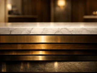 Bar counter front with a white marble top and stacked brass-gold metal panels in warm, dim lighting