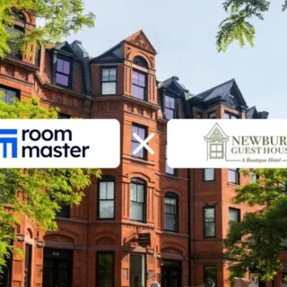 Red brick building with green trees and a banner showing the Room Master logo crossed with the Newbury Guest House logo.