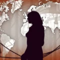 Silhouettes of people separated by chains in front of a world map backdrop, suggesting global isolation or barriers.