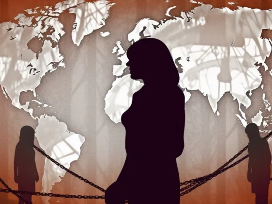 Silhouettes of people separated by chains in front of a world map backdrop, suggesting global isolation or barriers.