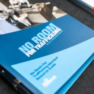 Blue pamphlet on a table with the bold title 'NO ROOM FOR TRAFFICKING', indicating an anti-trafficking awareness brochure.