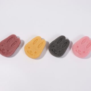 Five colorful gummy bear–shaped erasers with smiling faces lined along the bottom on a white background (red, yellow, gray, and pink).