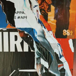 Close-up of a torn collage of colorful posters and paper scraps with visible text fragments and the number 88.